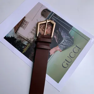 Detailopname van een bruine lederen riem met gouden geometrische gesp voor dames.