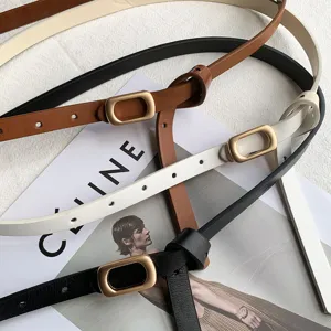 Minimalist thin leather belt detail, classic oval metal buckle, versatile trouser accessory.