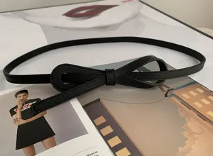Vue détaillée d'une fine ceinture en cuir noir avec un joli nœud, élégante et minimaliste.
