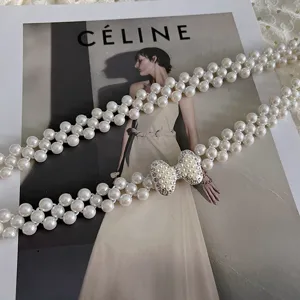 Close-up detail of elegant double-strand pearl waist chain with sparkling rhinestone bow.