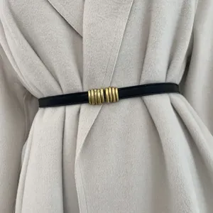 Primo piano dettagliato di una sottile cintura nera da donna con fibbia elegante in metallo dorato.