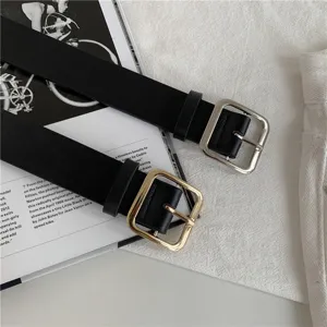 Detailed shot of stylish black leather women belt with square metal buckle on flat lay background.