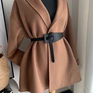 Women's stylish camel coat with black leather knot waist belt detail showing slim fit.