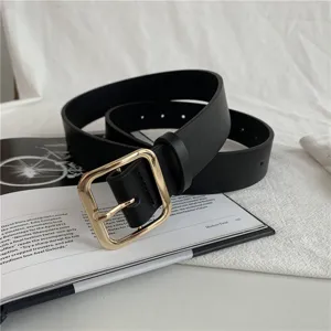 Close-up detail of the black women's leather belt with a stylish gold square metal buckle.
