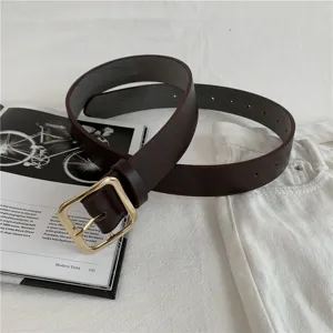 Detail shot of a brown women leather belt with a sleek gold square buckle on white.