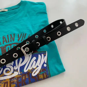 Punk style black leather belt with metal grommets for jeans and trousers fashion detail.