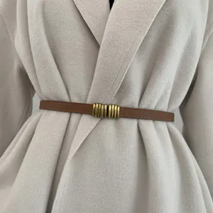 Primo piano di una sottile cintura in pelle marrone con fibbia dorata su un cappotto.