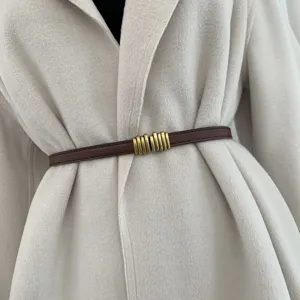 Primo piano di una sottile cintura in pelle marrone con fibbia in metallo dorato vintage.