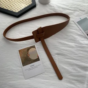 Detail shot of brown minimalist knot leather waist belt, stylish accessory for winter coats.