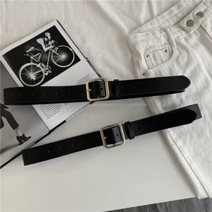 Detail shot of women's black leather belt with square metal buckle, classic design detail.