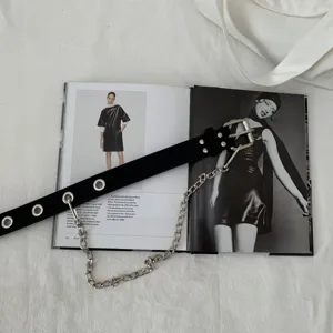 Detailed shot of a black punk leather belt featuring metal eyelets and a silver chain.