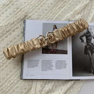 Cintura elastica dorata con fibbia in metallo, elegante accessorio per abito da donna.