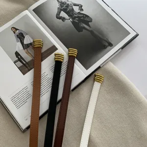 Dettaglio di sottili cinture in pelle con punte metalliche dorate, eleganti e raffinate.
