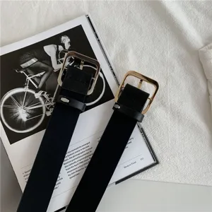 Close-up shot of black fashion women belts with shiny gold square metal buckles on mag.
