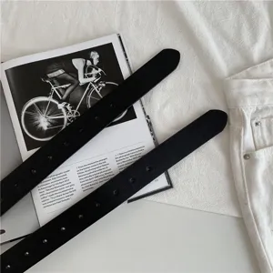 Detailed view of minimalist black women's belts featuring multiple eyelet holes and sleek design.