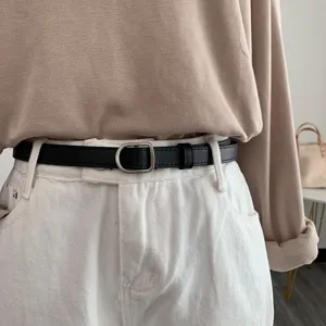 Minimalist black leather belt detail, metal D-ring buckle, versatile jeans accessory.