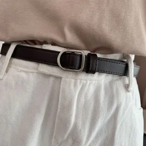 Close-up of retro dark brown thin leather belt with silver metal buckle, outfit detail.