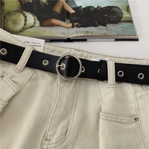 Women black leather waist belt with metallic round buckle, stylish pants accessory detail shot.