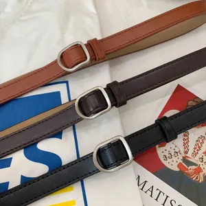 Close-up detail of thin leather belt featuring smooth metal buckle and premium texture.