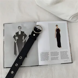 Detailed view of black leather women belt featuring silver round metal buckle and eyelet grommets.