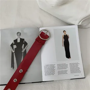 Detailed shot of a stylish red leather womens belt featuring a chic silver round buckle.