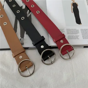 Close up detail of women fashion leather belts with large round metal buckles and eyelets.