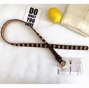 Vue détaillée d'une ceinture fine en cuir marron avec œillets et boucle ardillon métallique.
