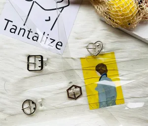 Dettaglio cintura trasparente in PVC con diverse fibbie ad ardiglione in metallo geometrico.