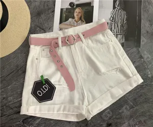 Close-up detail of white denim shorts with a pink belt and stylish hexagonal buckle.