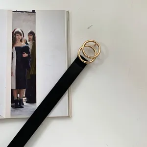 Detailed view of a minimalist black leather belt featuring a chic gold double-ring buckle.