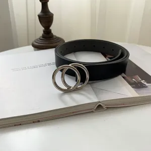 Minimalist black leather belt with silver double O-ring metal buckle, detail view.