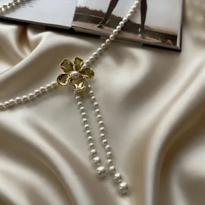 Vue détaillée de la chaîne de taille perlée de luxe avec pendentif fleur dorée élégante.