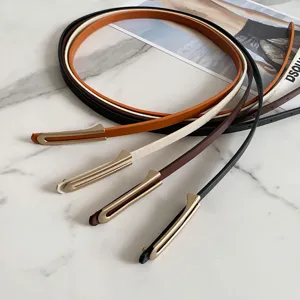 Primo piano dettagliato di sottili cinture in pelle minimaliste con eleganti passanti in metallo.