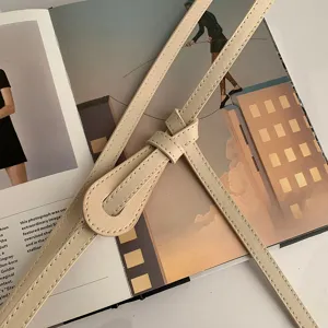 Vue en gros plan de la ceinture en cuir beige élégante dotée d'un nœud chic et stylé.