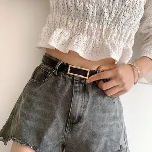 Detailed shot of a stylish minimalist women's leather belt with a sleek rectangular metal buckle.