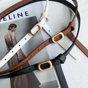Close-up detail of stylish women's thin belts in black, white, and brown with metal oval buckles.