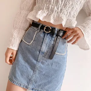 Minimalist black leather belt for women with gold round buckle, stylish denim jeans accessory.