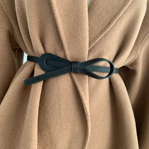 Vue détaillée d'une élégante ceinture fine en cuir noir nouée sur un manteau.