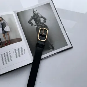 Ceinture en cuir noir minimaliste avec boucle dorée, détail de mode élégant et tendance.