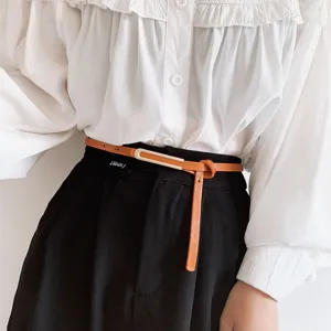 Vista dettagliata della cintura sottile in pelle marrone da donna con fibbia in metallo.