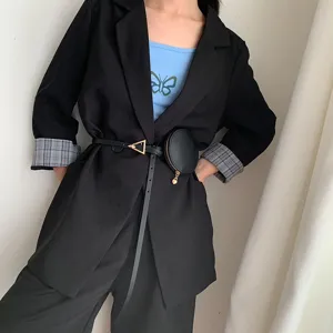 Donna elegante cintura sottile in pelle nera con fibbia in metallo a triangolo e piccolo marsupio.