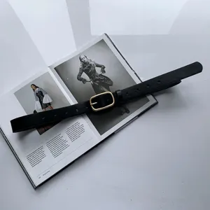 Détail rapproché d'une élégante ceinture noire en cuir dotée d'une boucle carrée dorée.