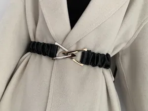 Close-up detail of women elastic waist belt with metal interlocking triangle buckle.