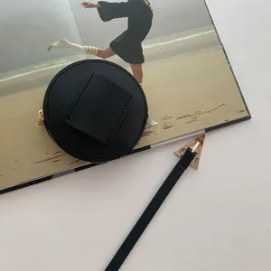 Cintura nera in pelle alla moda con mini marsupio tondo e fibbia metallica triangolare dorata.