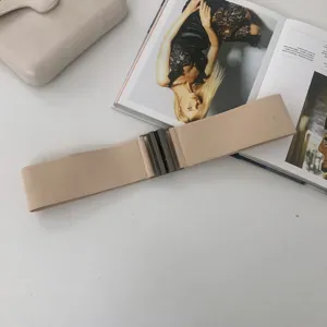 Wide elastic stretch waist belt in beige featuring a dark metallic interlock buckle design.