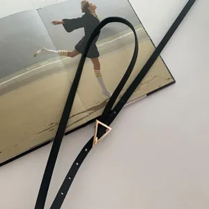 Cintura sottile in vera pelle nera da donna con fibbia triangolare dorata per outfit di tendenza.