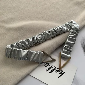 Metallic pleated elastic waist belt with modern metal triangle buckle detail close up view