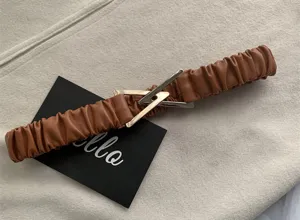 Women brown pleated elastic waist belt with metallic triangle buckle, minimalist design.
