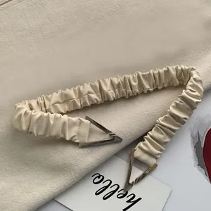 Beige elastic waist belt featuring distinctive metal triangle buckle design detail.