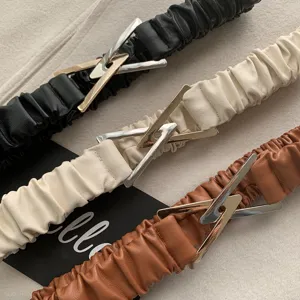 Close-up detail of stretchy wide waist belts with unique triangular metal buckles in three colors.